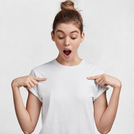 Isolated shot of attractive female with amazed look, keeps mouth widely opened, indicates at blank t shirt, poses against white studio background, expresses surprisment. People, clothing, advertisment
