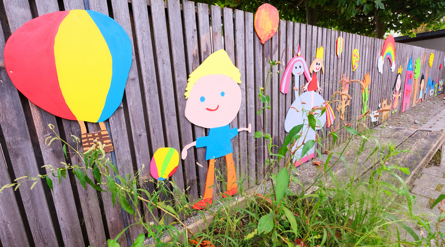 Diese Abbildung zeigt einen von Kindern bunt dekorierten Gartenzaun.