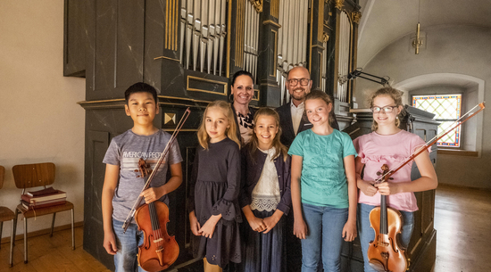 Diese Abbildung zeigt Bürgermeister Michael Ritsch mit einer weiteren Dame und fünf Kindern. Zwei von den Kindern halten ihre Violine in der Hand.