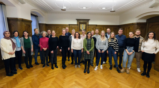 Gruppenbild der neuen Lehrpersonen im Schuljahr 2023/2024, die im Stadtvertretungszimmer im Bregenzer Rathaus nebeneinander aufgestellt sind und in die Kamera lächeln.