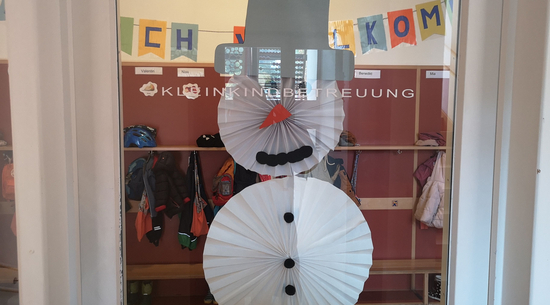 Hier wurde die Eingangstüre der Kleinkindbetreuung in Bregenz fotografiert. Auf die Türe wurde ein selbstgebastelter Schneemann aufgeklebt. Im Hintergrund ist die Garderobe der Kinder zu sehen.