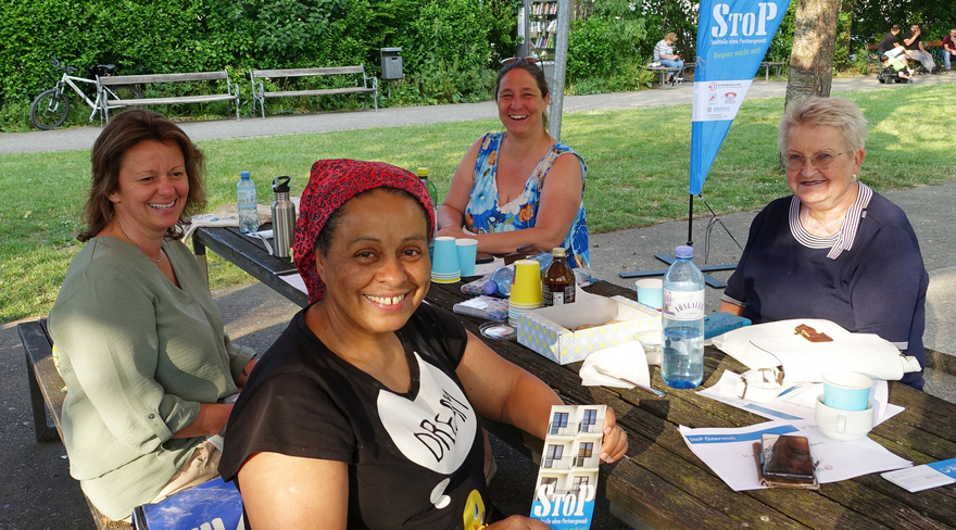 Vier Damen beim Ein Treffen der Aktionsgruppe StoP im Park Mariahilf, die um einen Holztisch sitzen. 