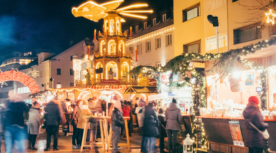 Diese Abbildung zeigt den Bregenzer Weihnachtsmarkt am Kornmarktplatz bei Nacht.