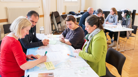 Das Bild zeigt Teilnehmer:innen beim KliB40-Workshop 2024. Sie arbeiten an einem Tisch Klimastrategien für Bregenz aus.