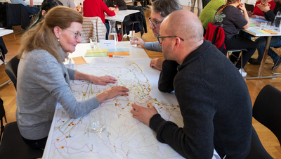 Das Bild zeigt Teilnehmer:innen beim KliB40-Workshop 2024. Sie arbeiten an einem Tisch Klimastrategien für Bregenz aus.