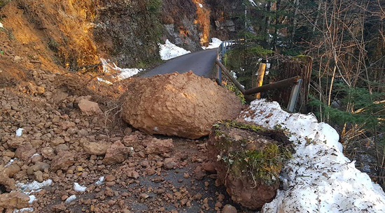 Auf dem Foto ist eine beschädigte Straße durch einen Felssturz zu sehen. 