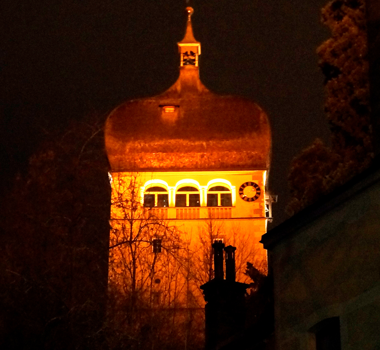 Diese Abbildung zeigt den orange angeleuchteten Martinsturm bei Nacht.